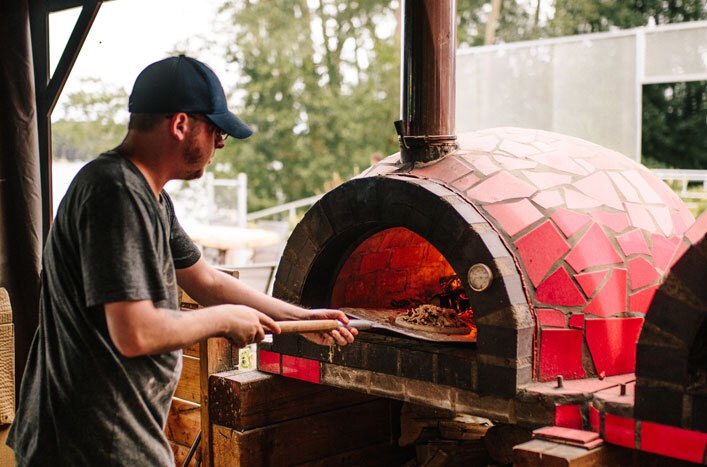 Le chef enfourne une pizza dans le four à bois du Chack